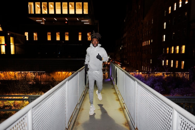 Jonge man loopt 's nachts op een brug in de stad