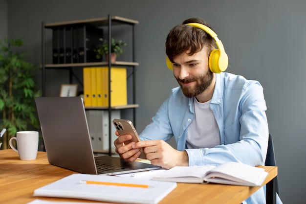 Jonge man luisteren naar muziek op koptelefoon tijdens het werken