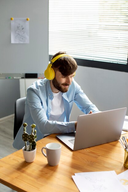 Jonge man luisteren naar muziek op koptelefoon tijdens het werken