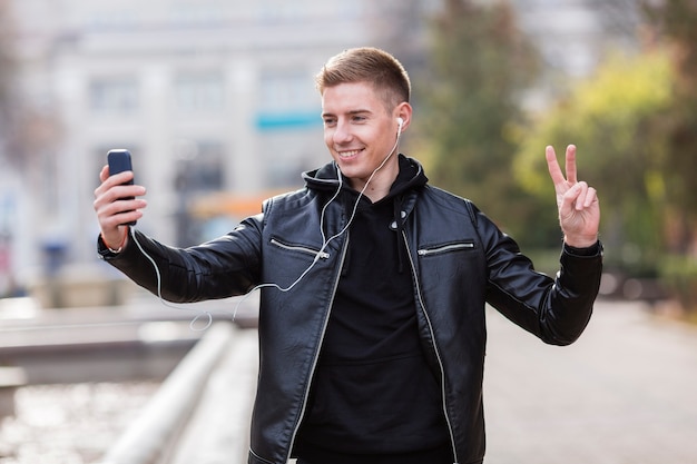 Jonge man luisteren naar muziek op oortelefoons terwijl het nemen van een selfie
