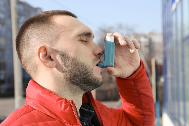 Jonge man met astma-inhalator op straat