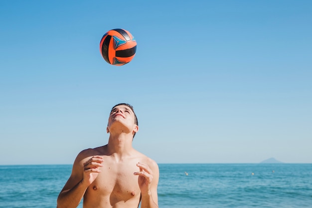 Jonge man met bal op het strand