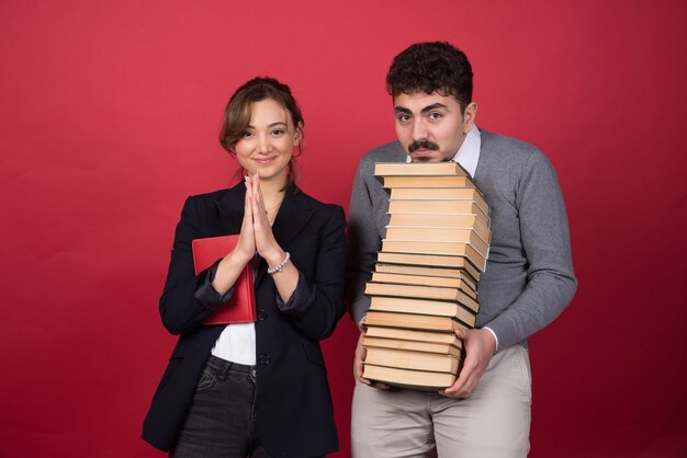 Jonge man met bosboeken en vrouwencollega die voor camera stellen