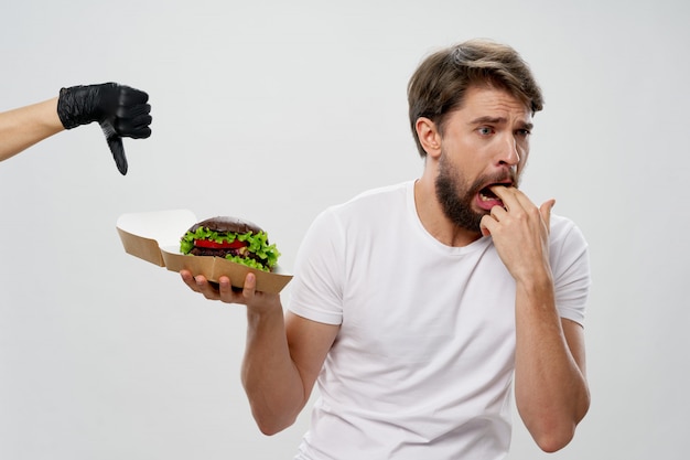 Jonge man met een sappige hamburger in zijn handen, een man die een hamburger eet