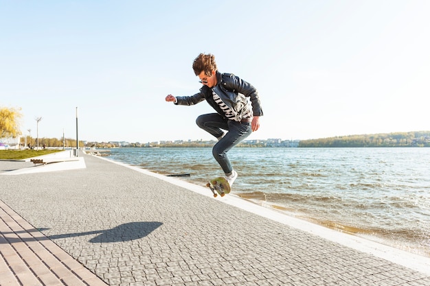 Gratis foto jonge man met een skateboard in de buurt van de zee