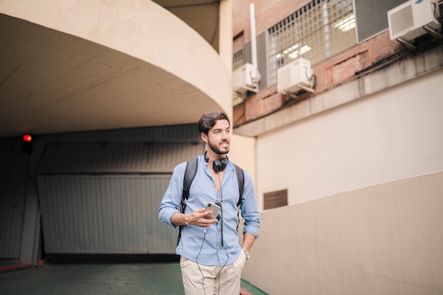Jonge man met een smartphone staande in de buurt van gebouw