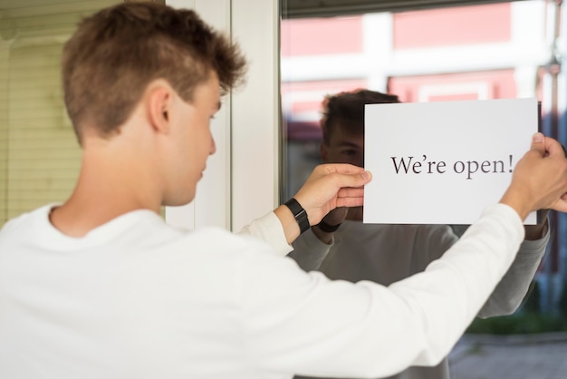 Jonge man met een teken dat we open zijn na het einde van de quarantaine