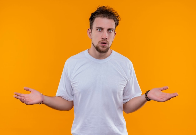 Jonge man met een wit t-shirt dat toont wat gebaar op geïsoleerde oranje muur