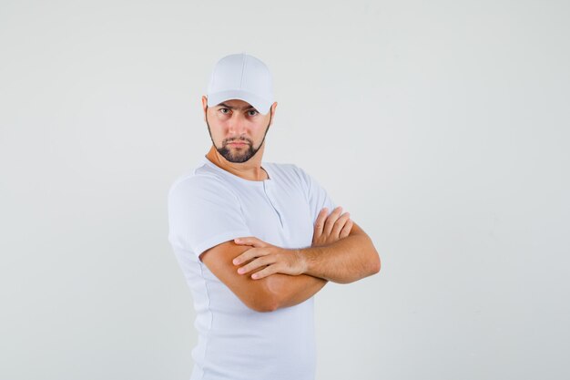 Jonge man met gekruiste armen in wit t-shirt en op zoek strikt. vooraanzicht.