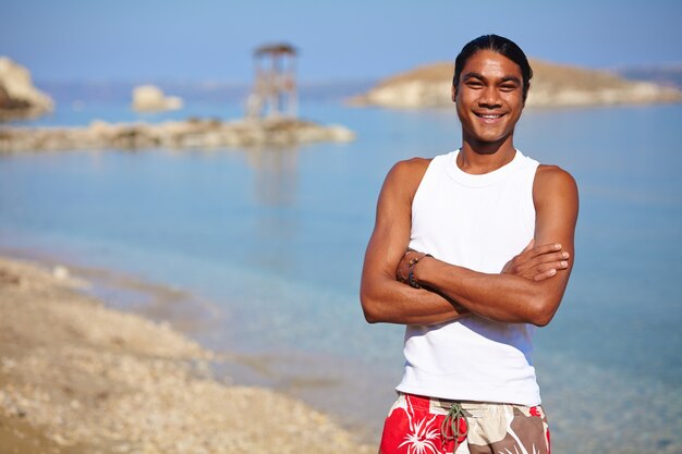 Jonge man met gekruiste armen op het strand