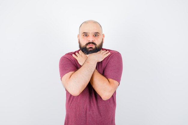 Jonge man met hand op keel in roze t-shirt vooraanzicht.