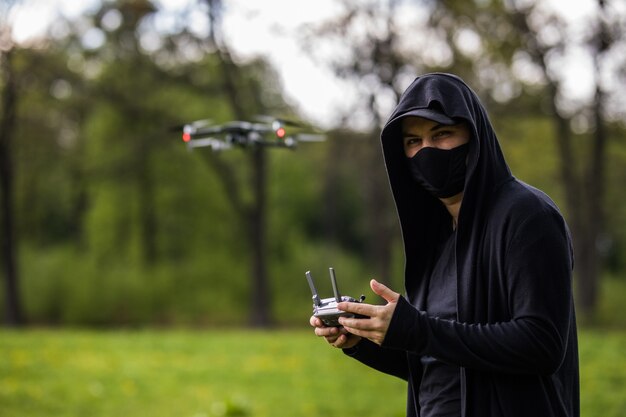 Jonge man met masker gebruikt afstandsbediening voor drone in het bos