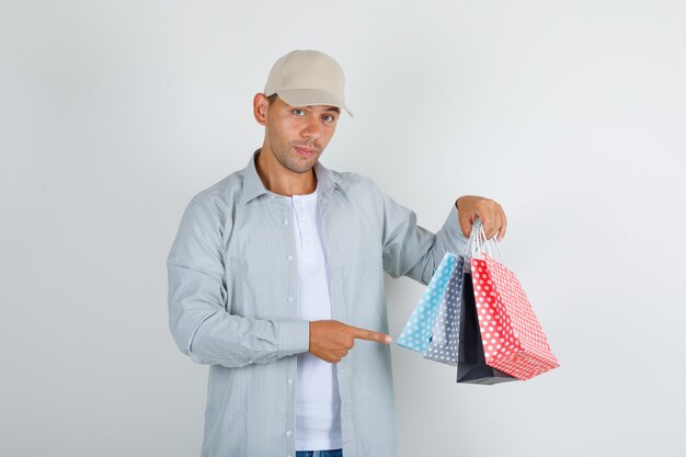 Jonge man met papieren zakken in shirt met pet, jeans