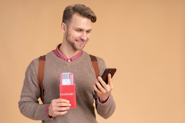 Jonge man met paspoort en smartphone om te reizen