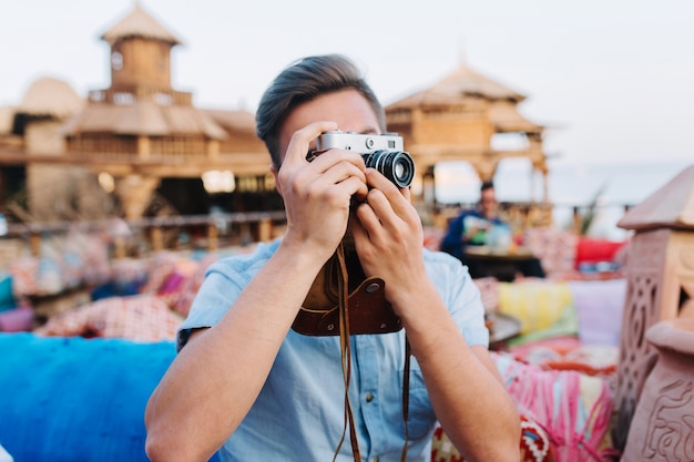 Jonge man met professionele retro camera rusten op terras, vrienden te wachten