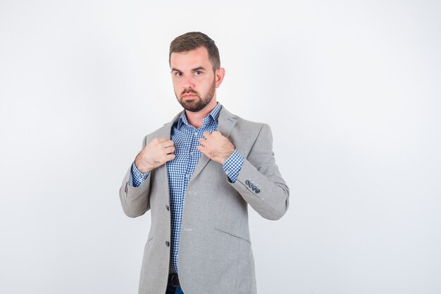 Jonge man met revers terwijl poseren in shirt, spijkerbroek, colbert en op zoek naar serieuze, vooraanzicht.