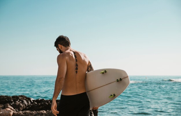 Jonge man met surfplank in de buurt van de oceaan