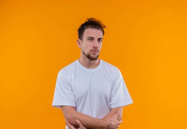 Jonge man met wit t-shirt handen kruisen op geïsoleerde oranje muur