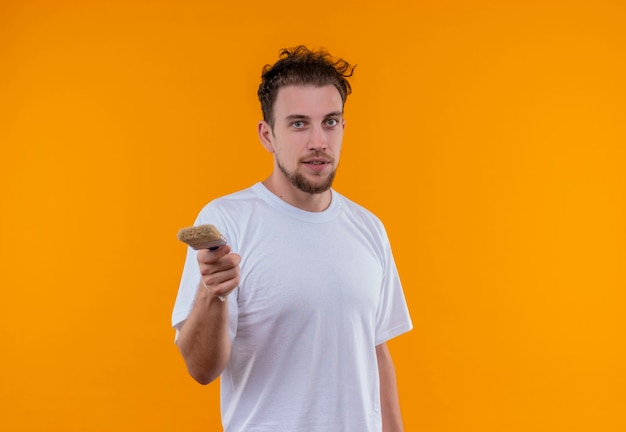 jonge man met wit t-shirt met kwast op geïsoleerde oranje muur