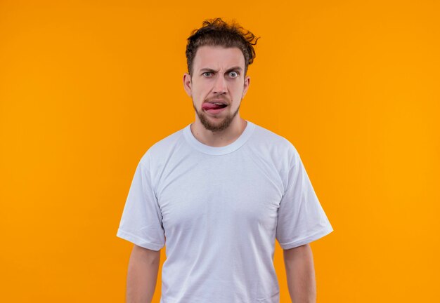 jonge man met wit t-shirt met tong op geïsoleerde oranje muur