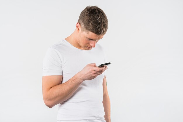 Jonge man met zijn mobiele pone tegen een witte achtergrond