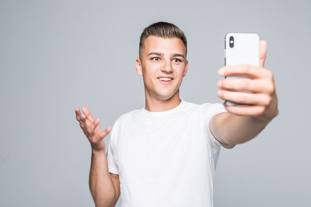 Jonge man neemt selfie geïsoleerd op grijs