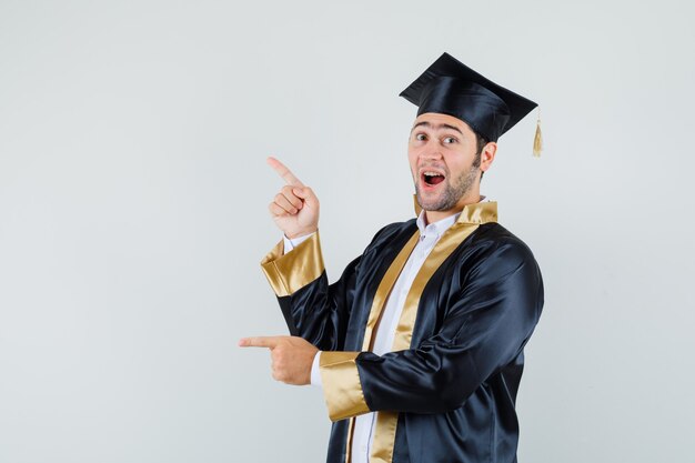 Jonge man omhoog en opzij in afgestudeerde uniform en kijkt blij, vooraanzicht.