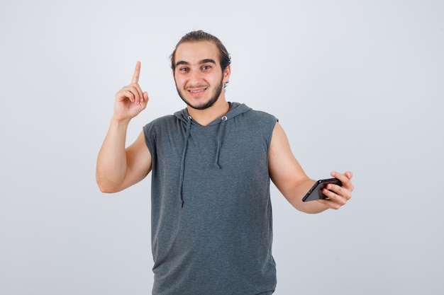 Jonge man omhoog in t-shirt met een kap en kijkt gelukkig, vooraanzicht.