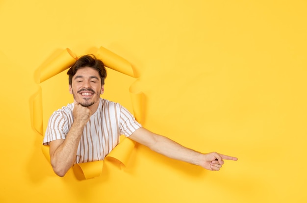 Jonge man op zoek van gescheurde gele papieren achtergrond man verkoop binnen