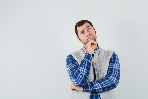 Jonge man opzoeken in shirt, mouwloos jasje en op zoek doordachte, vooraanzicht. ruimte voor tekst