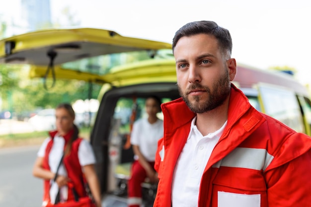 Gratis foto jonge man paramedicus staat achter de ambulance paramedici bij de ambulance twee paramedici komen uit de ambulance