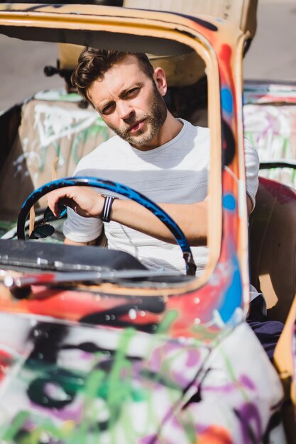 jonge man poseren tegen de achtergrond van een vintage auto