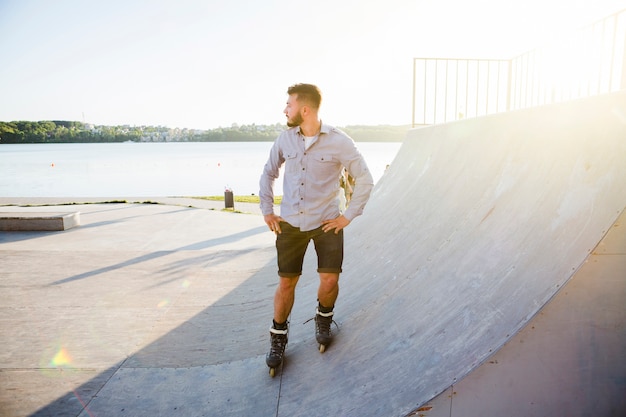 Jonge man rolschaatsen in skatepark tijdens zonnige dag
