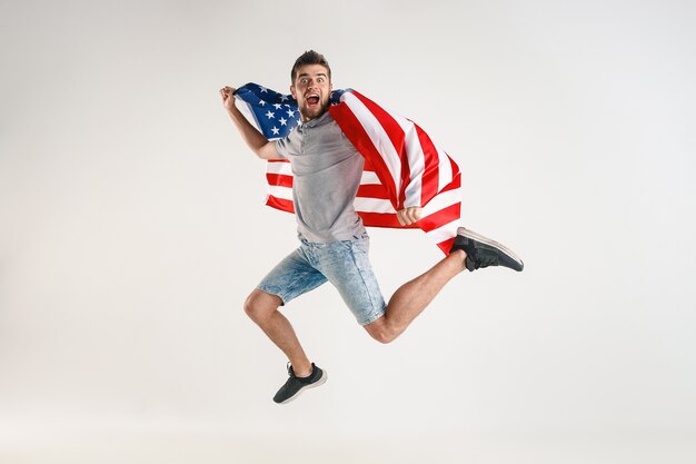 Jonge man springen met vlag van de Verenigde Staten van Amerika geïsoleerd op witte studio.