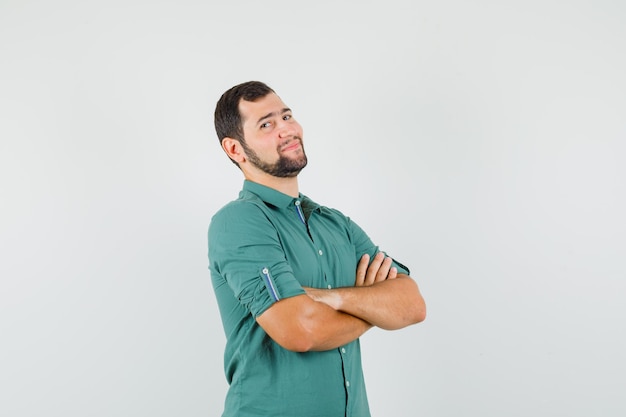 Jonge man staat met gekruiste armen in groen shirt en ziet er zelfverzekerd uit, vooraanzicht.