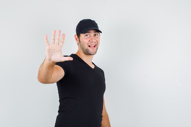 Jonge man stop gebaar beleefd tonen in zwart t-shirt