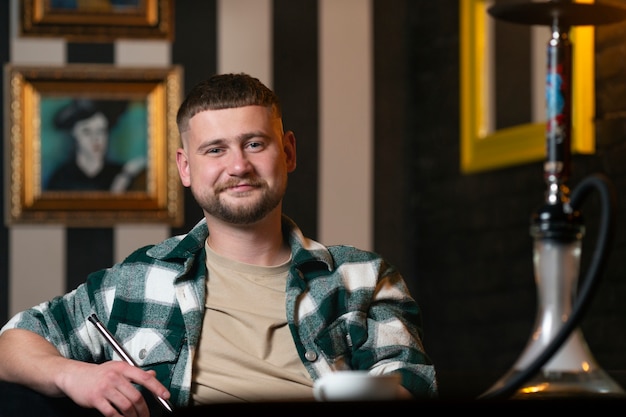 Jonge man vapen van een waterpijp in een bar