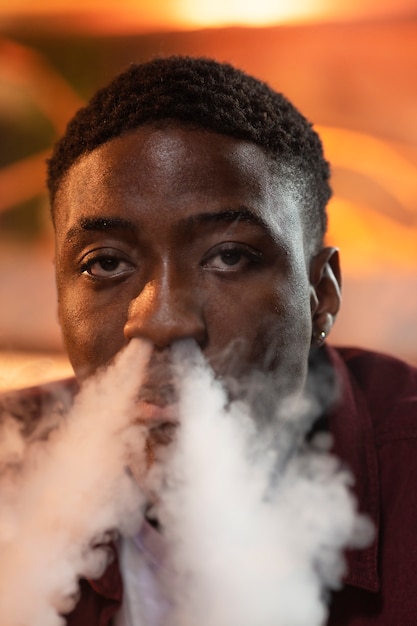 Gratis foto jonge man vapen van een waterpijp in een bar