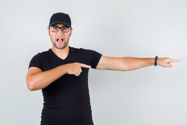 Jonge man wijst naar kant in zwart t-shirt