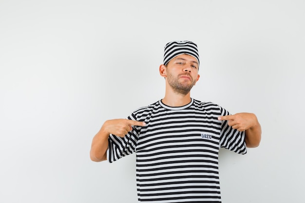 Jonge man wijzend op zichzelf in gestreepte t-shirt hoed en op zoek trots
