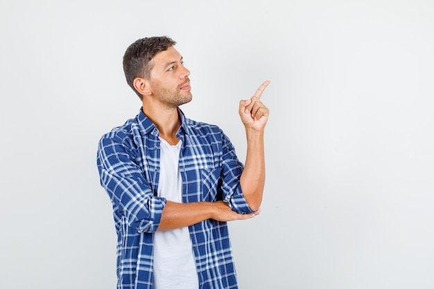 Jonge man wijzende vinger naar kant in shirt en op zoek gericht. vooraanzicht.