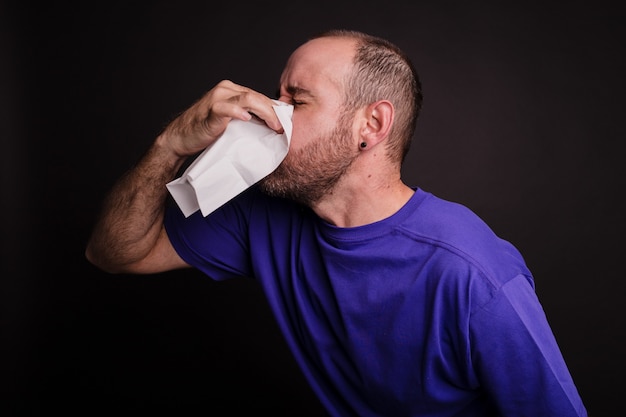 Jonge man zijn neus afvegen met een papieren handdoek