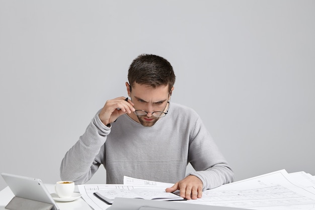 Jonge man zit aan bureau en doet papierwerk