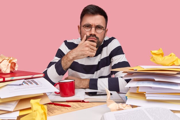 Jonge man zit aan bureau met documenten