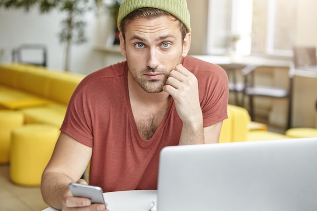 Jonge man zit in café met laptop