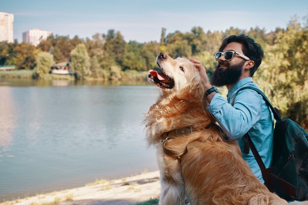 Jonge man zit met zijn hond op de stoel in het park