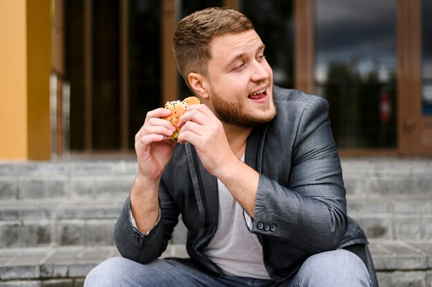 Jonge man zitten met eten in zijn handen