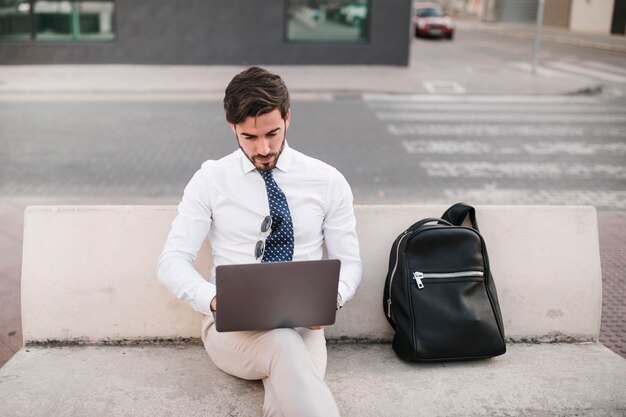 Jonge man zittend op de bank werkt op laptop