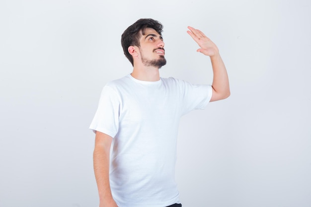 Jonge man zwaaiend met de hand om afscheid te nemen in t-shirt en er vrolijk uit te zien