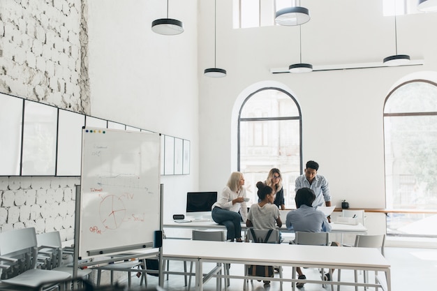 Jonge managers en CEO tijd doorbrengen in de conferentiezaal in de ochtend. Indoor portret van team van marketeers bespreken nieuwe doelen in grote moderne kantoren.